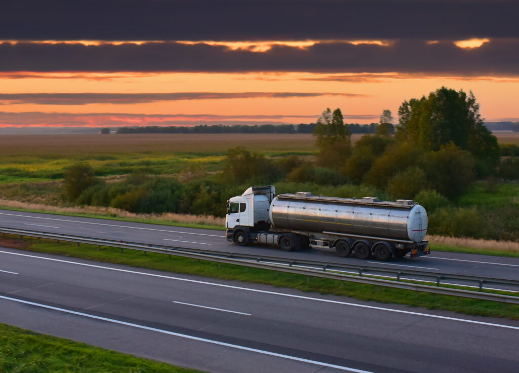 Isothermal Tank truck driving on highway. Oil and Gas Transportation and Logistics. Metal chrome cistern tanker with petrochemicals products. Liquid Chemical Freight